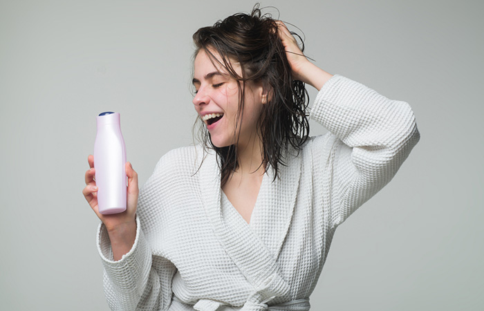 Woman holding a bottle of regular shampoo after taking a bath.