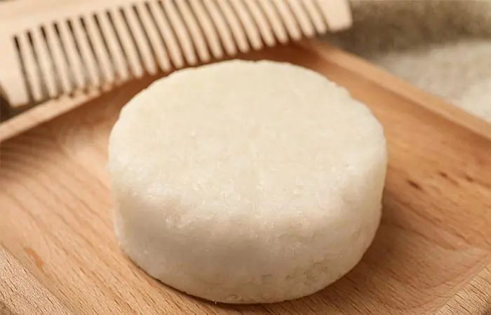 A white shampoo bar placed on a wooden tray