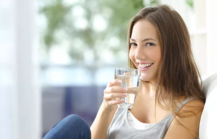 Woman hydrating herself by drinking water to achieve beautiful skin