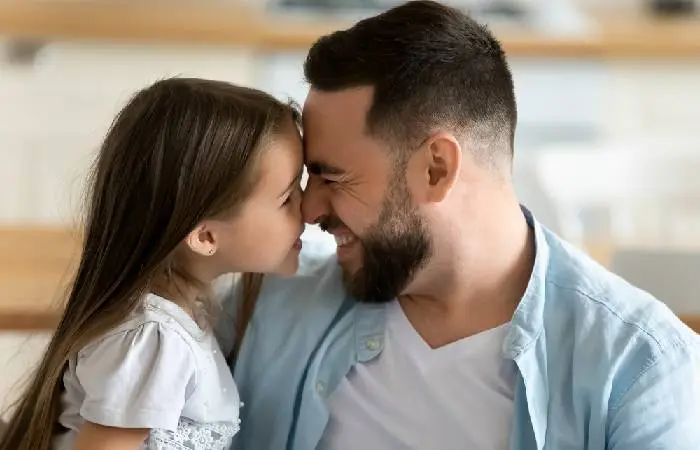 A father happily touches nose with his daughter’s nose 