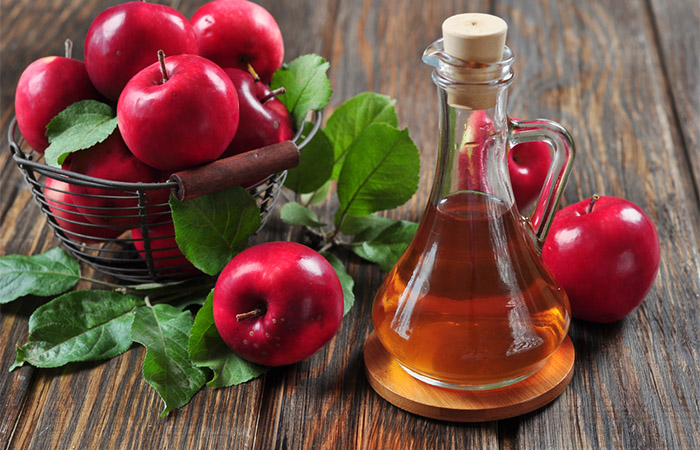 Apple cider vinegar in glass bottle and a basket of fresh apples.