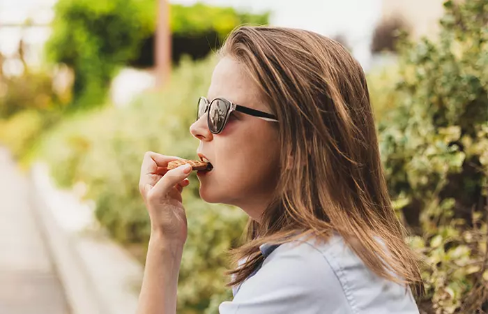 Side view of woman eating a digestive biscuit