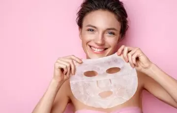 Smiling woman holding a face sheet mask