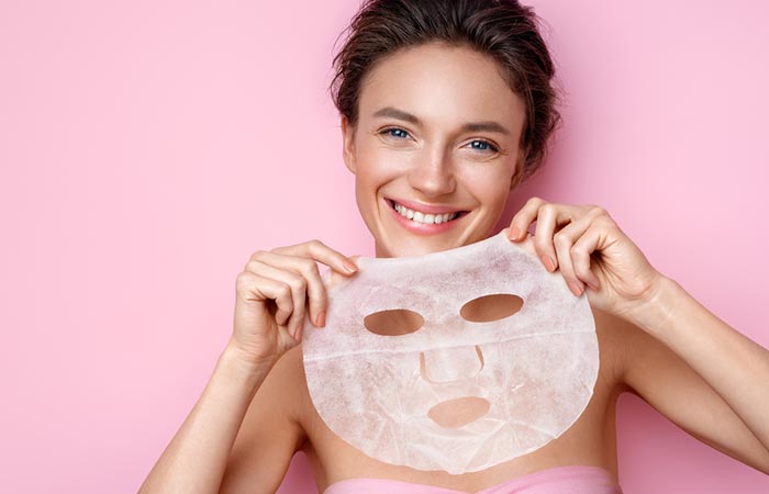 Smiling woman holding a face sheet mask