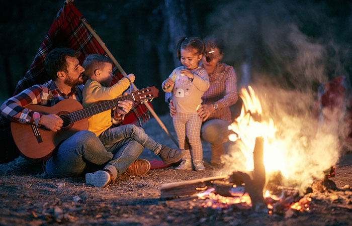 Family playing music and sharing stories around a bonfire