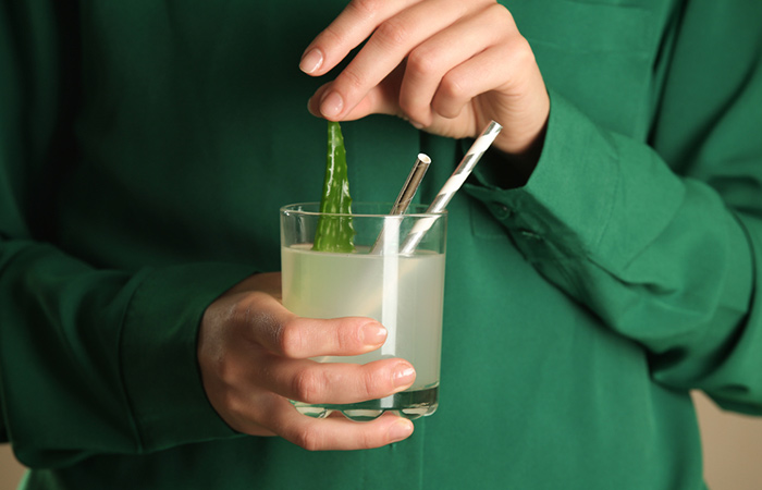 Close up of a woman holding a glass of fresh aloe vera juice