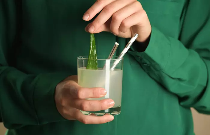 Close up of a woman holding a glass of fresh aloe vera juice