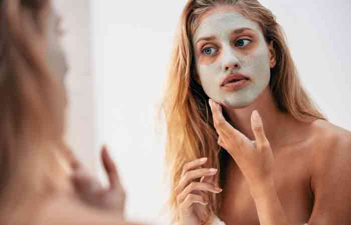 Woman using clay mask to prevent oily skin. 
