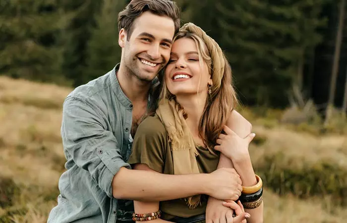 A lovely couple posing in the backdrop of a forest happy in each other's company