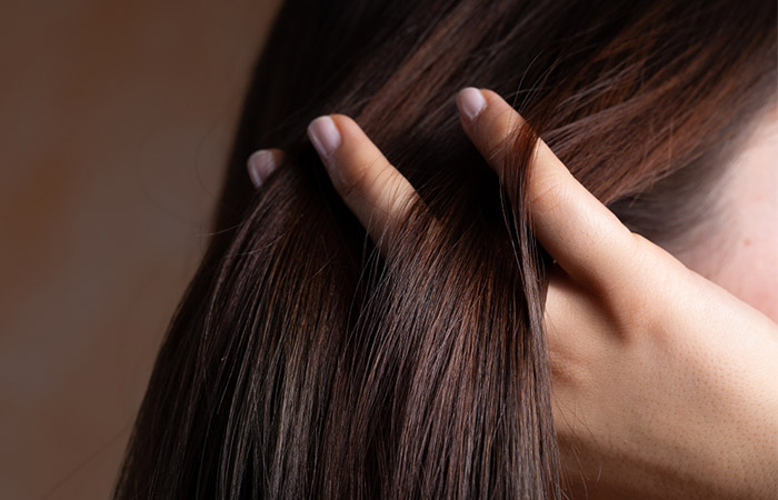 Closeup of woman running fingers through permanently straightened hair that is conditioned and well maintained