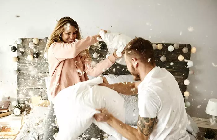 A couple having fun pillow fighting with each other.
