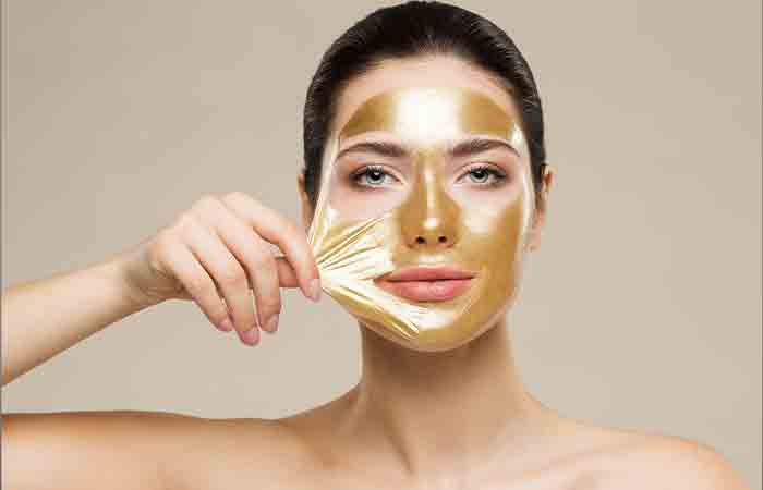 Woman peeling off gold face mask