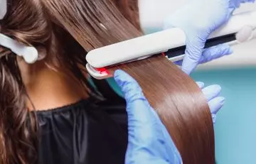 A woman getting permanent straightening done for her hair by a professional