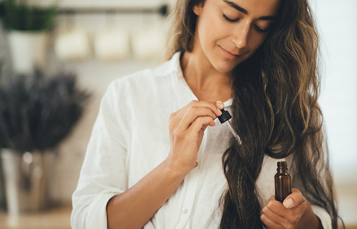 Woman applying essential oil to her frizzy hair