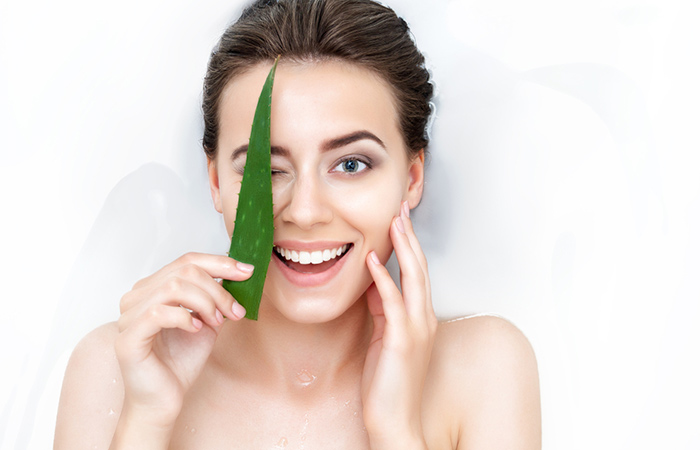 Woman with healthy skin posing with fresh aloe vera 