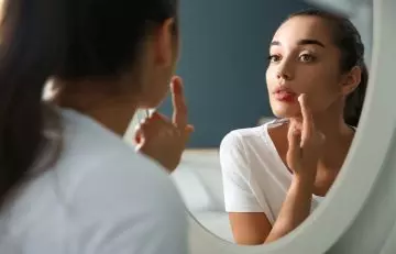 Woman applying ointment to pimples on her lips
