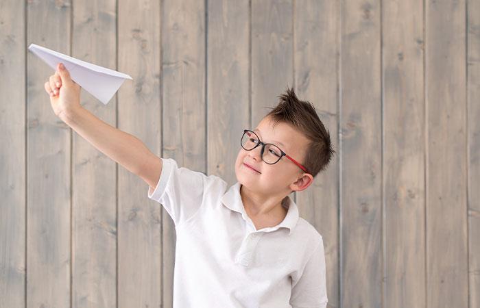 A young girl playing with a paper plane