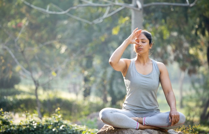 woman-practicing-yoga-lotus-position-park-1669079605