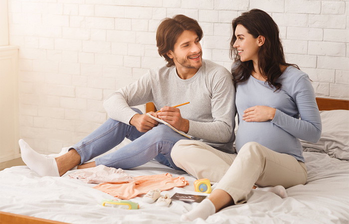 A pregnant woman and her partner sitting with each other and smiling.