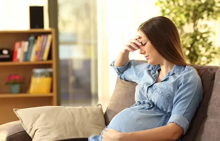 A pregnant woman is sitting frustrated.