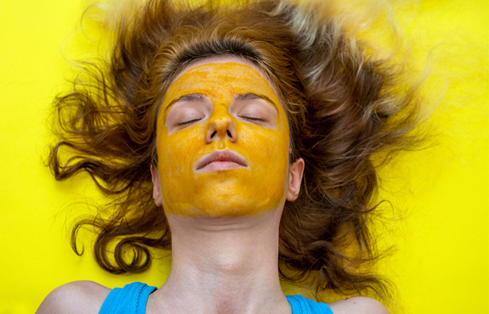 A woman can be seen with turmeric facemask lying on her back.