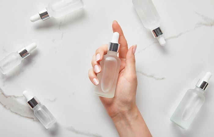 Hand with a bottle of serum and more bottles in the background