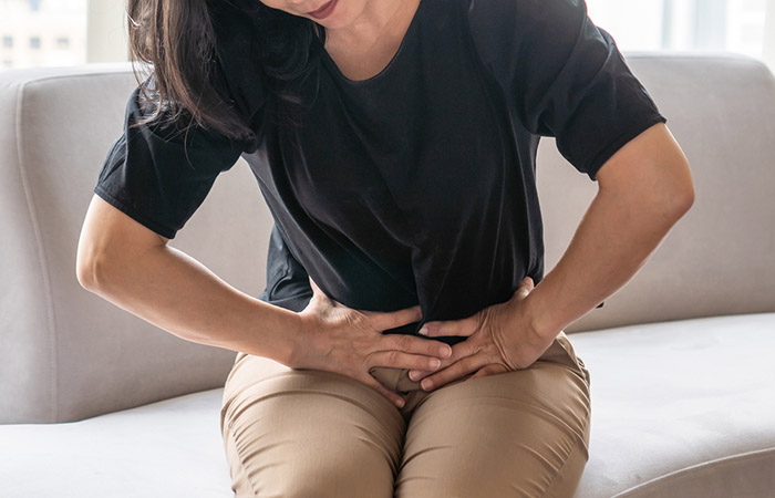Woman experiencing indigestion as a potential side effect of saw palmetto
