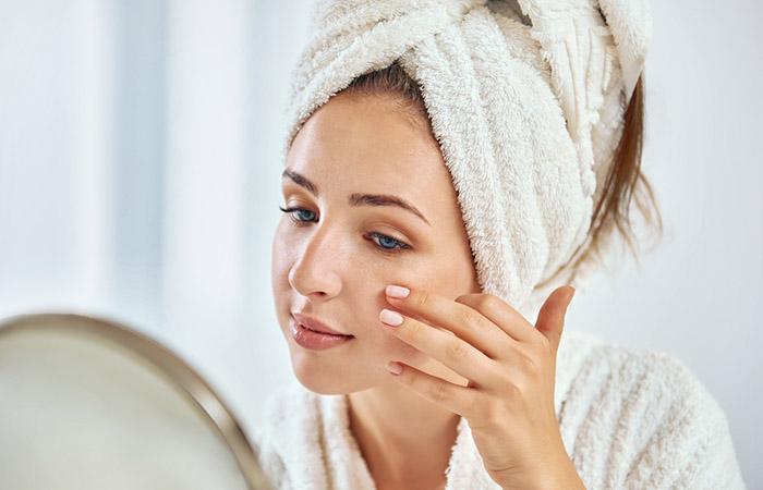 Woman looking at her smooth skin after exfoliation