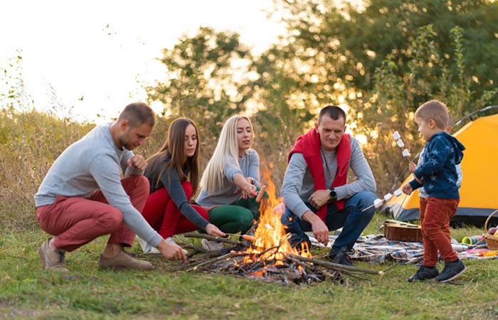 A family is setting up a bonfire to cook marshmellows.