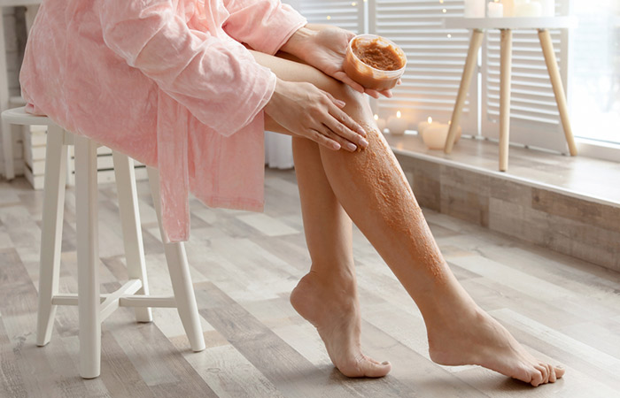 Young woman using cucumber and rose water scrub on the legs