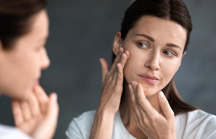 Woman checking her face in the mirror for acne
