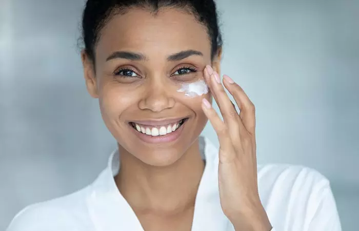 A woman is applying milk cream on her face.