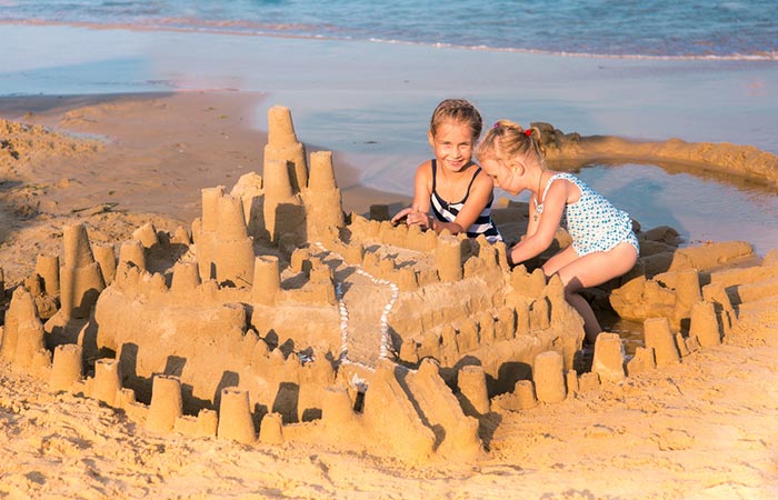 Young girl building a sandcastle with her friend
