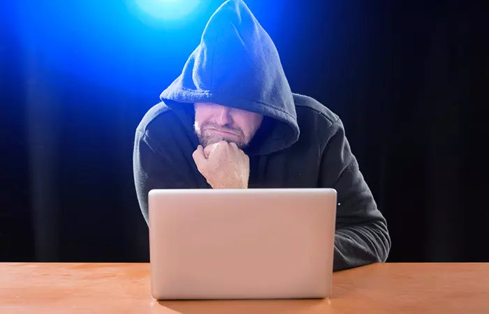 Hooded stalker in front of a computer 