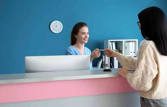 Woman paying at the reception desk of a Forma skin tightening center