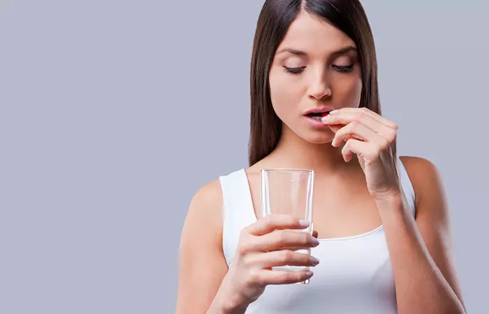 Woman taking prescribed pill to treat acne papules