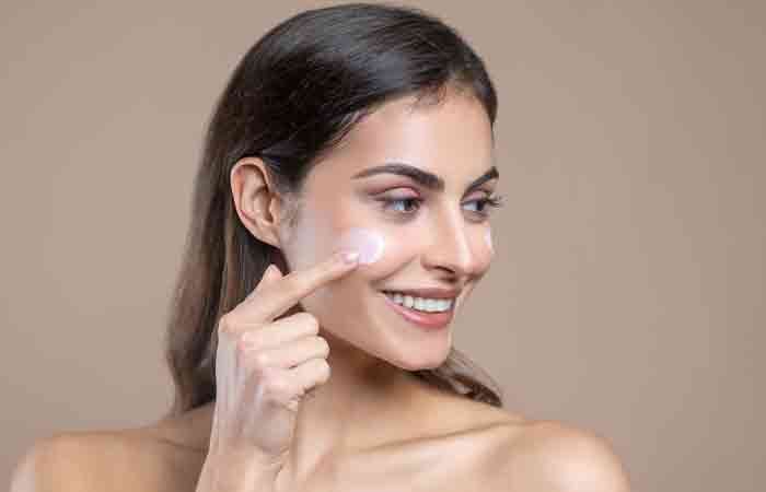Woman applying astaxanthin moisturizer on her face