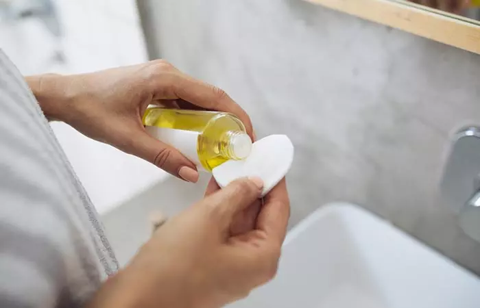 Woman soaking cotton pad with neem oil