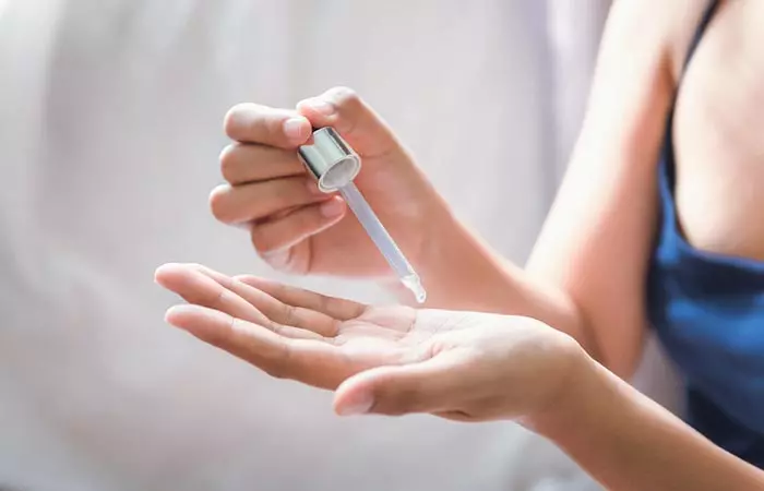 Woman takes a few drops of PHA serum to apply on her face