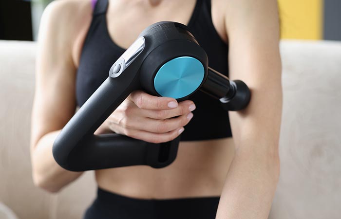 Fit and athletic woman massaging her arm with a tool