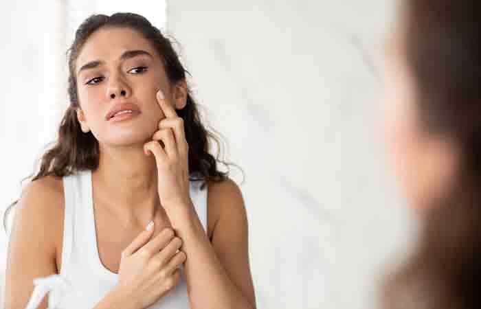 Woman examines pimple on her face may benefit from tallow for skin care