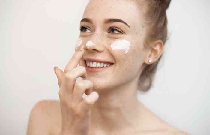 Young woman moisturizing her skin