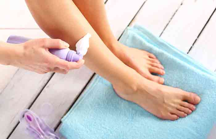 Woman applying shaving foam on legs before shaving hair to prevent ingrown hair