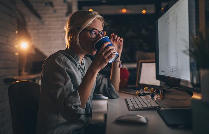 Busy woman working late into the night and drinking coffee
