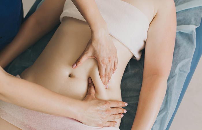 Woman receiving skin fold massage on the abdominal region