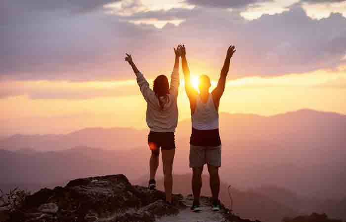 Couple celebrate reaching the top of a hill as a team