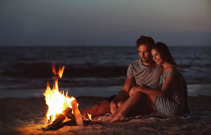 Couple sitting near a bonfire.