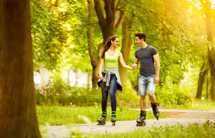 A couple roller skating in a park.