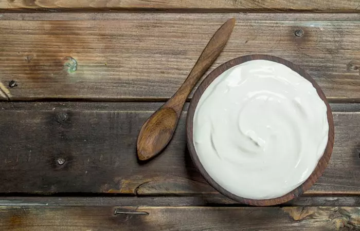 An overhead shot of a wooden bowl filled with malai or milk cream.