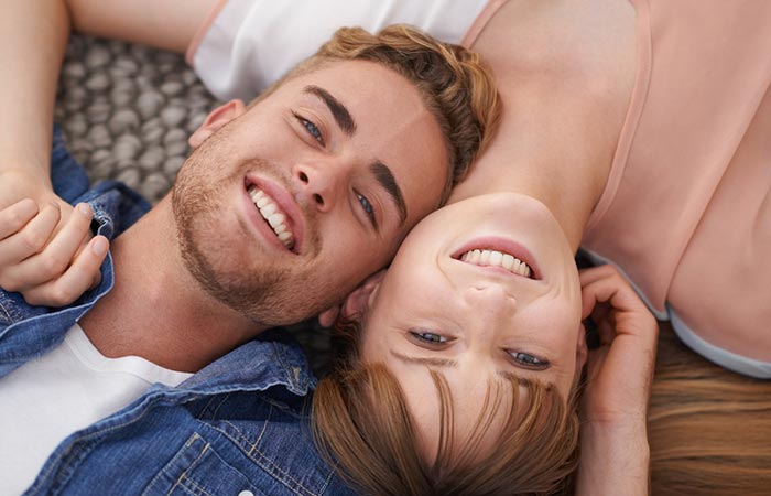 A monogamous couple smiling and lying on the floor.